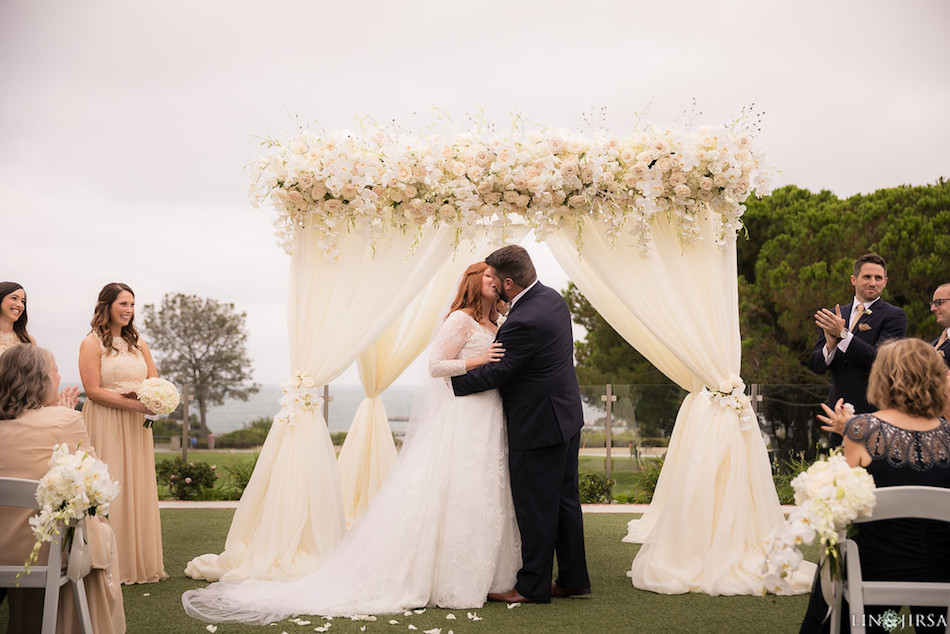 first kiss, newlyweds, bride, groom, arch, wedding flowers, enchanting laguna cliffs marriott, flowers by cina