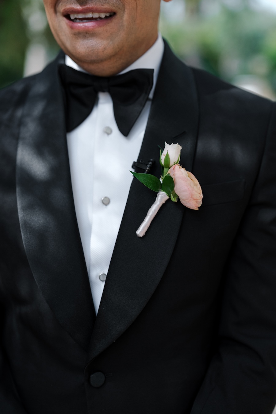 Groom in black tux with blush floral boutonniere. 