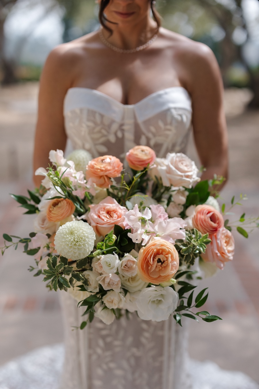 Bride holding bouquet of flowers that are peach, blush, and white. 